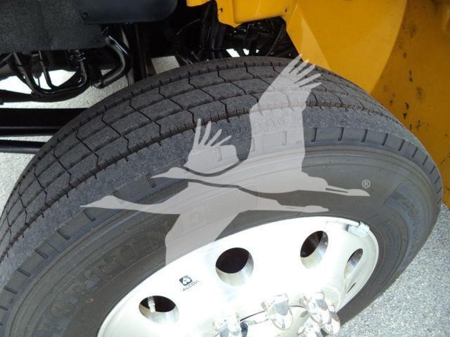 Truck wheel and fender with tire and rim; visible text on tire sidewall reads 'Goodyear' and 'Endurance' with numbers, plus part of the truck frame and yellow body.