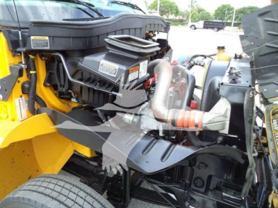 Truck engine bay of a 2019 International 4300 rollback showing engine components, hoses, and surrounding yellow bodywork.