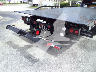 Truck bed with hydraulic rollback system and rear bumper setup on a 2019 International 4300 rollback truck showing flatbed surface and rear hitch components.