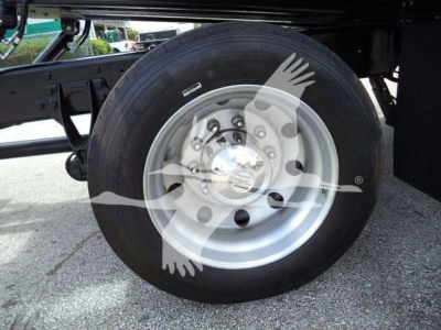 Truck wheel and dual rear axle area showing a silver steel wheel with lug nuts and a large black tire, undercarriage supports visible.