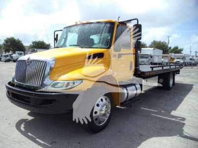 Truck cab and flatbed rollback with bright yellow International 4300 front view showing chrome grille and dual rear wheels.