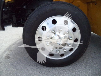 Wheel and tire on a heavy truck front hub with chrome rim and lug nuts visible.