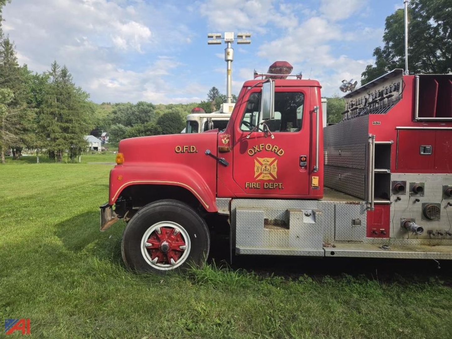 Side view of an antique fire truck with Oxford Fire Dept emblem, red cab, metal steps, and equipment compartments.