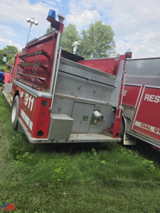 Fire truck rear quarter showing equipment bay doors and ladder storage with '9311' visible on the side.