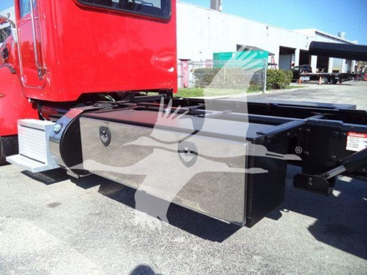 Peterbilt 337 rollback truck side view showing large metal tool/storage box under cab and chassis frame with red cab in background.