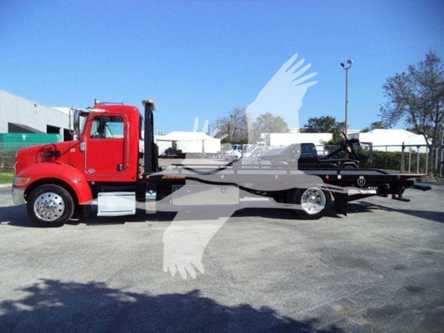 Peterbilt 337 rollback truck in red cab and long flatbed, side view with clear cab, wheels, and chrome fuel tanks.