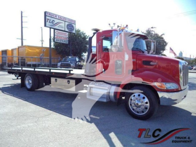 Peterbilt 337 rollback tow truck in red with flatbed, side view showing chrome wheels and equipment on bed.