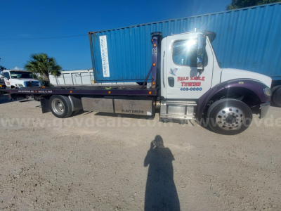 Freightliner M2 tow truck in blue and white with flatbed, side text shows Wooley’s Towing and 407-0000; VIN 1FVACWFCXKHKJ5474 not visible but on listing.