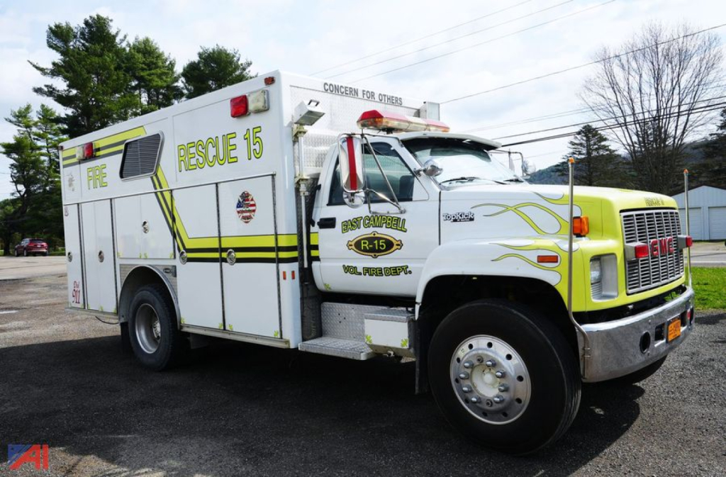 GMC Topkick E-One rescue truck with 'RESCUE 15' markings and yellow-green flame graphics, side compartments, and front chrome bumper.
