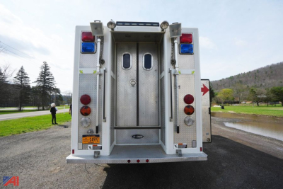 Rear view of a GMC Topkick/E-One rescue fire truck showing dual rear doors, ladder storage, and stacked red/blue emergency lights.