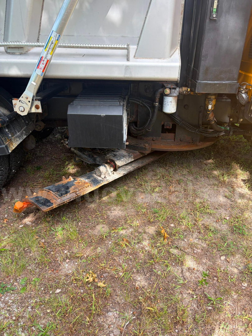 Rear-right side of a 2005 International 7300 dump truck showing a black plastic toolbox and hydraulic components near the undercarriage.