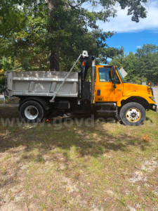 Yellow International dump truck with a hydraulic bed lift, side view showing the cab and dumping box.