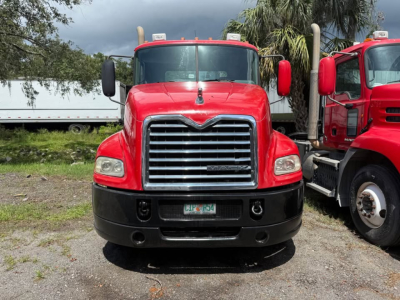 Front view of a red 2013 Mack CXU613 day cab truck showing chrome grille, headlights, bumper, and side mirrors.
