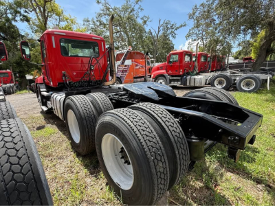 Truck chassis rear view showing dual rear axles and heavy-duty tires, red cab in background, Mack CXU613 likely field view.