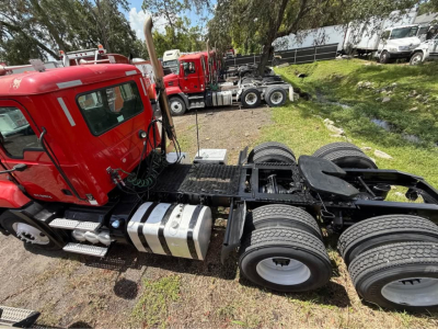 CXU613 truck chassis showing rear drive axle and fuel tanks with tires and cab in background.