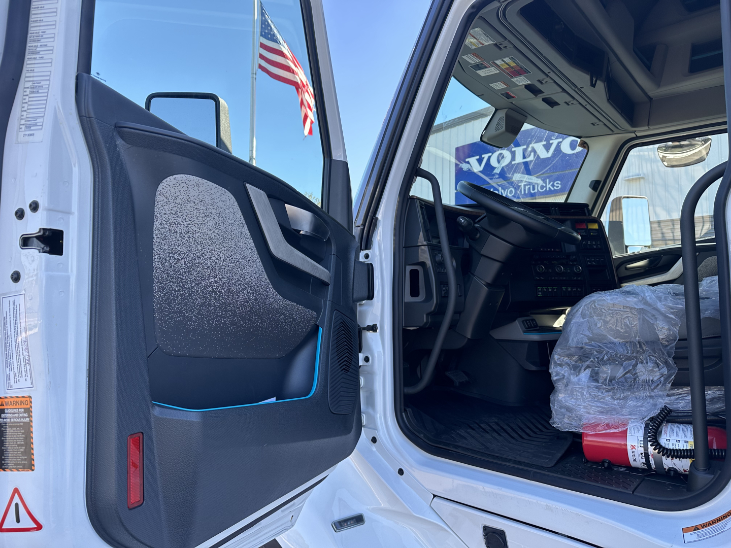 Volvo VNL64T860 truck cab interior with open door showing dashboard and steering wheel.