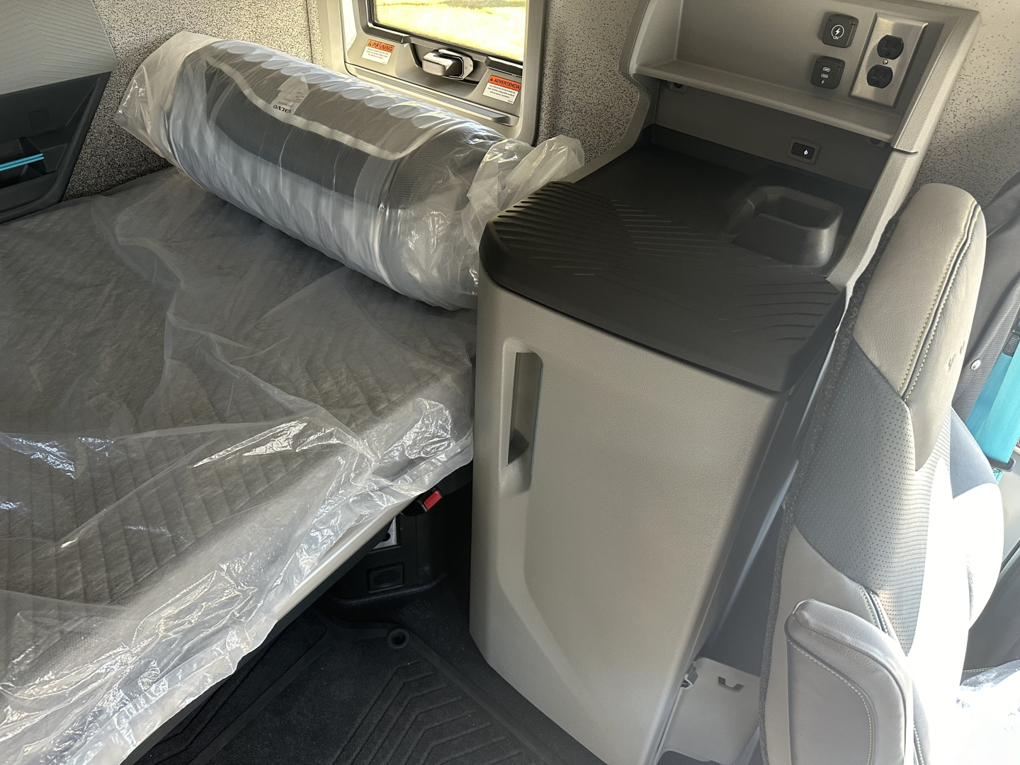 Interior of a 2025 Volvo VNL64T860 truck cab with plastic-wrapped sleeper bed and center console