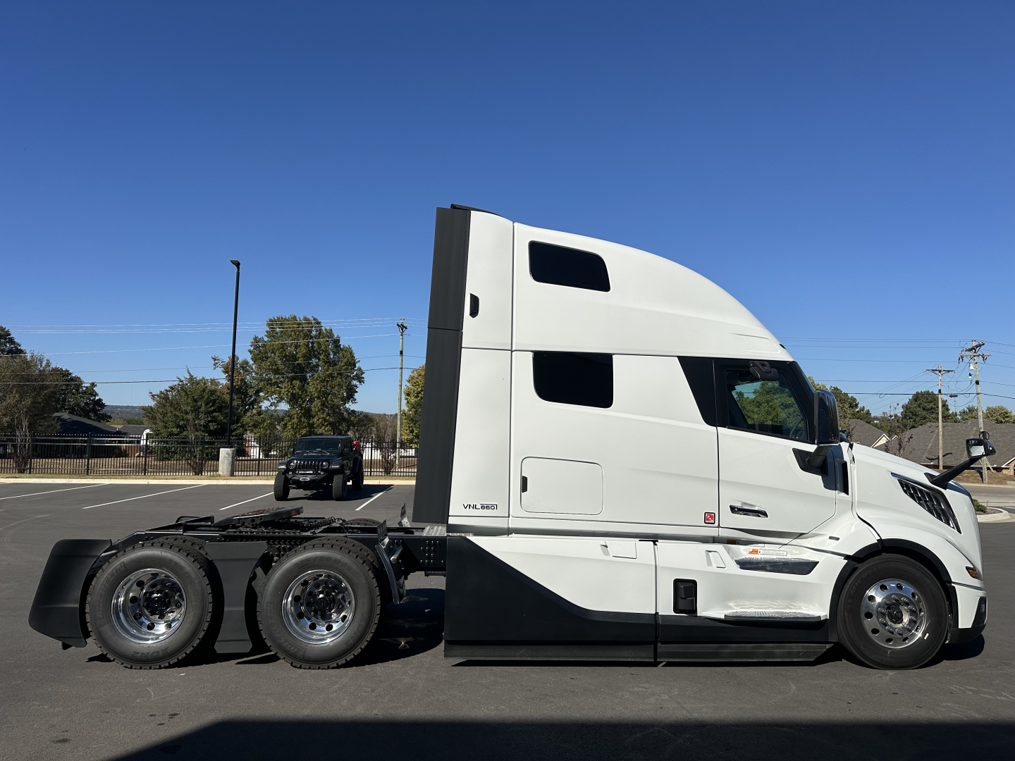 Volvo VNL64T860 sleeper tractor side view showing white cab with aerodynamic design and dual rear axles; no visible text on doors.