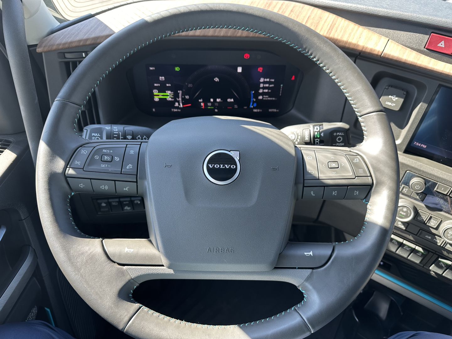 Volvo steering wheel and dashboard in a 2025 Volvo VNL64T860, showing digital instrument cluster and control buttons on steering wheel.