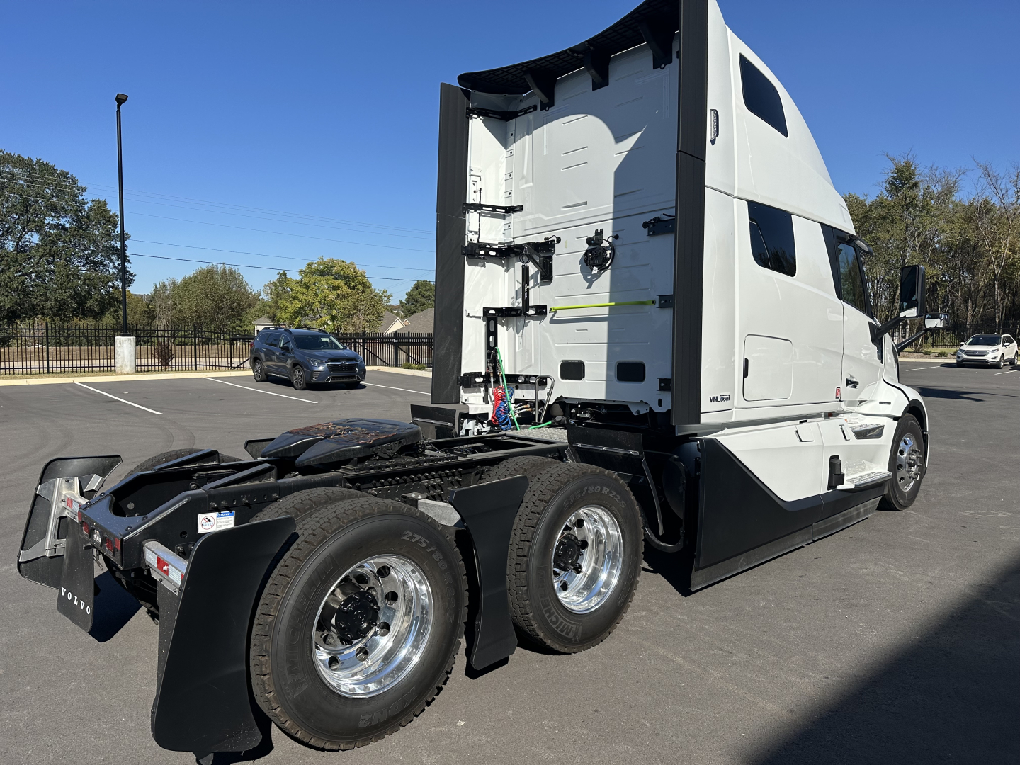 Volvo VNL64T860 truck tractor rear/side view showing sleeper cab and dual rear axles with chrome wheels.