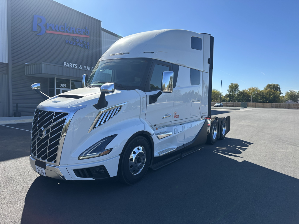 Volvo VNL64T860 tractor-trailer in white with sleeper cab, front grille, chrome mirrors, and dual rear axles parked outside dealership.