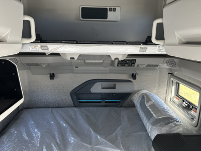 Volvo VNL64T860 sleeper cab interior showing overhead storage and control panel, window, and mattress area.