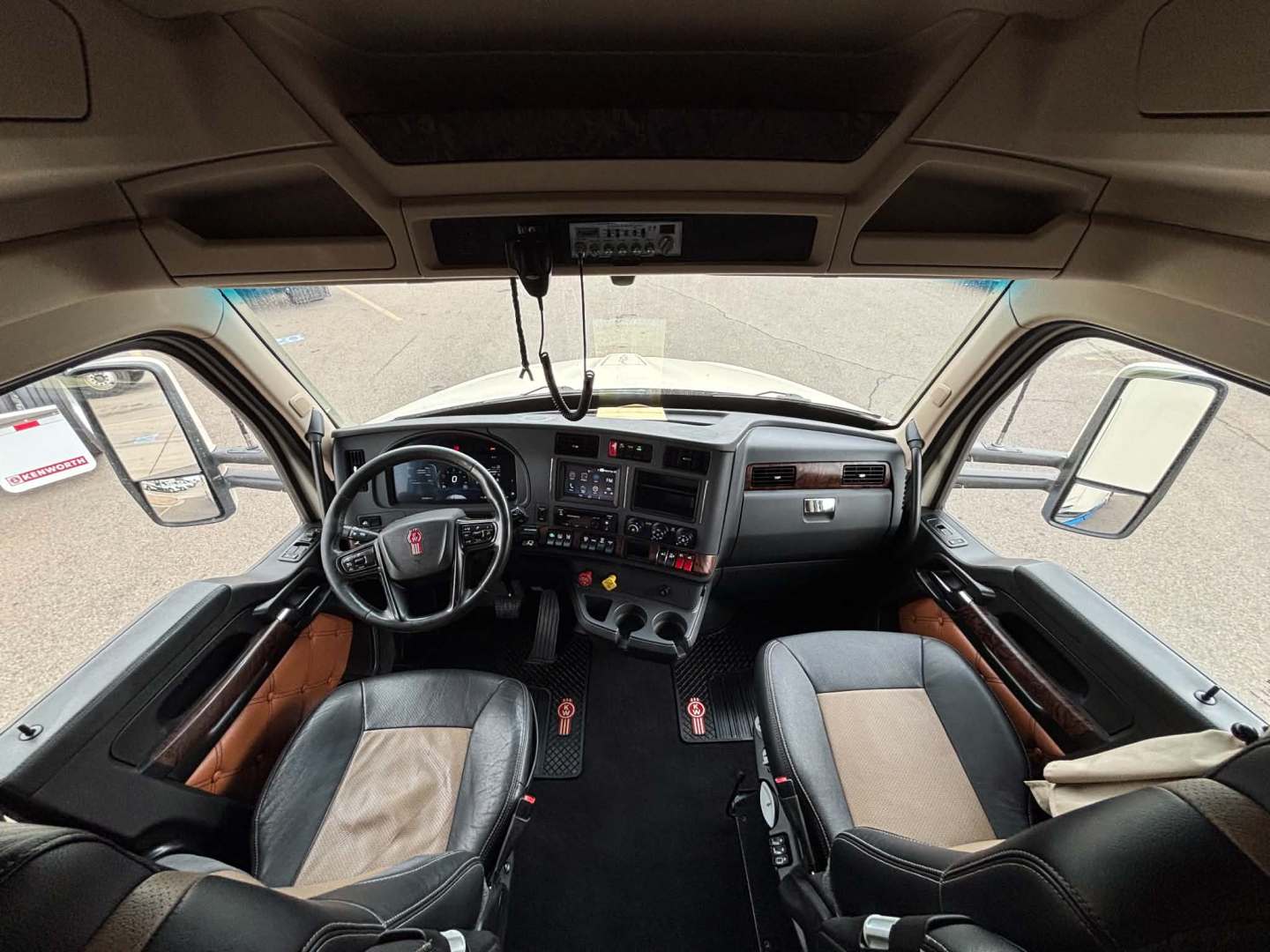 Truck cabin interior view of a Kenworth T680 dashboard with steering wheel, center console, and seats. No legible labels visible.