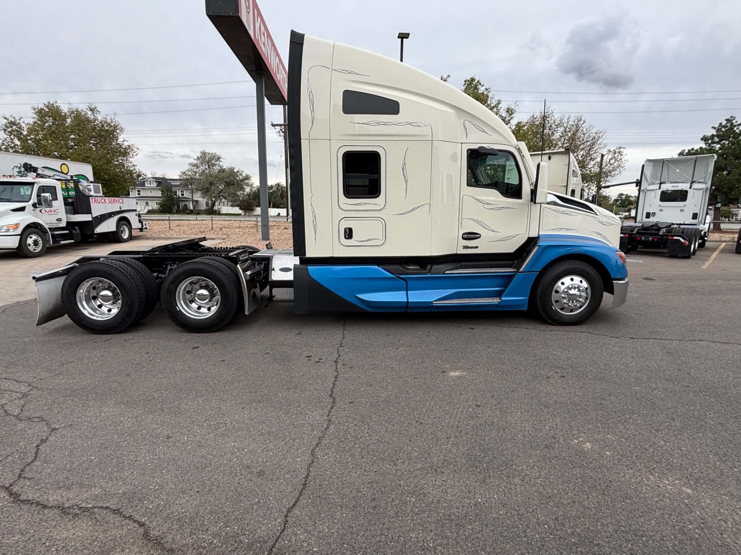 Kenworth T680 tractor in Side view showing cab, blue lower body accents, and triple rear axles.
