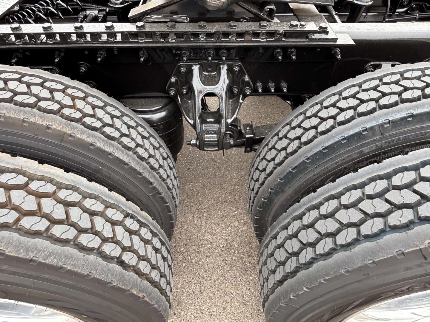 Kenworth T680 undercarriage showing tandem rear axles and suspension components between dual rear tires.