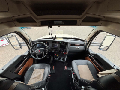 Truck cabin interior view of a Kenworth T680 dashboard with steering wheel, center console, and seats. No legible labels visible.