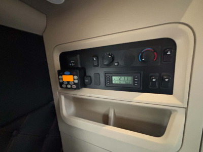 Kenworth T680 dash panel with climate controls, radio, and a small device attached to the left; visible text on the radio display and controls.