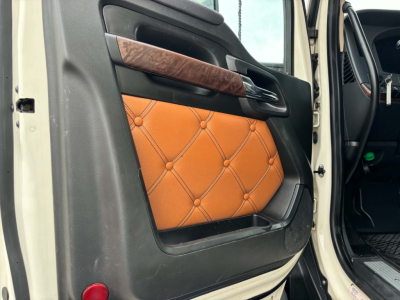 Kenworth T680 interior door panel view with tan diamond-quilted armrest and wood trim