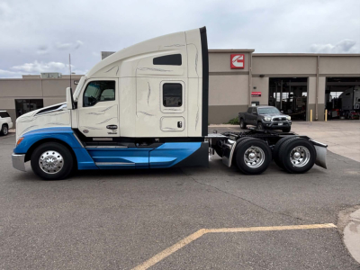Kenworth T680 tractor with sleeper cab, side view showing two-tone white and blue paint, nozzle and wheel area.