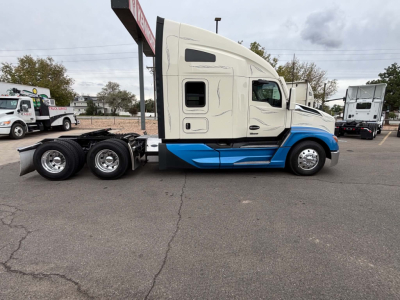 Kenworth T680 tractor in Side view showing cab, blue lower body accents, and triple rear axles.