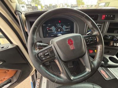 Kenworth T680 truck interior showing steering wheel with Kenworth emblem and dashboard controls.