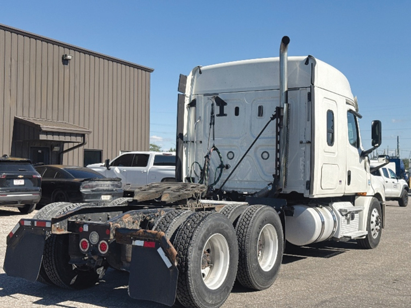 Freightliner Cascadia126 sleeper cab tractor in a lot, rear view shows dual rear axles and fifth wheel.