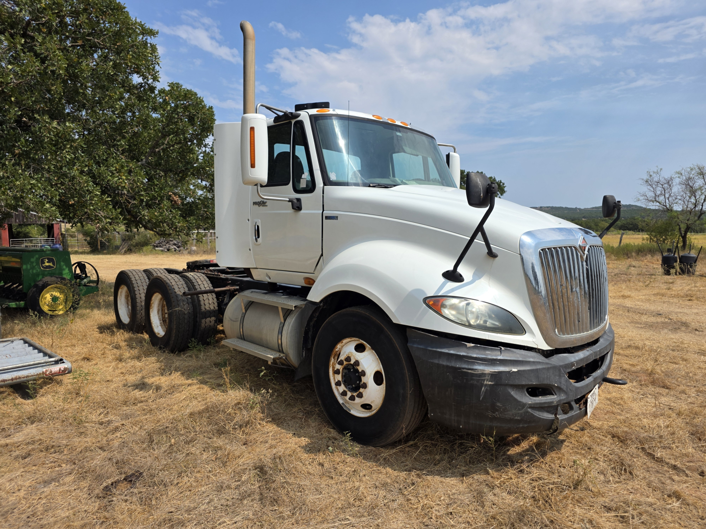 2009 International Prostar day cab truck shown in an outdoor lot with a white cab, high exhaust stack, and dual rear axles.