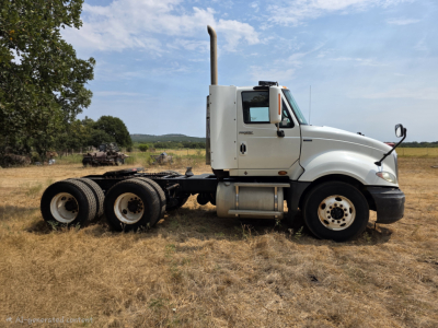 2009 International Prostar day cab tractor shown in side profile with a white cab and dual rear axle, grassy field background.