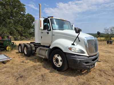 2009 International Prostar day cab truck shown in an outdoor lot with a white cab, high exhaust stack, and dual rear axles.