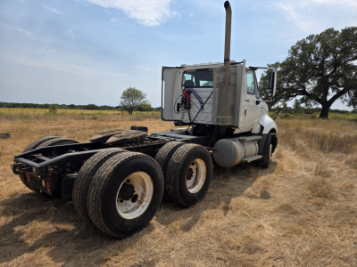 International Prostar day cab truck viewed from rear-left with tractor frame and dual rear axles on a field.