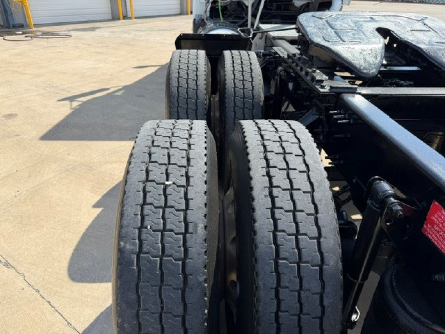 Volvo VNR64T300 truck chassis showing dual rear axles with four tires and suspensions; view focuses on tire tread and undercarriage components.