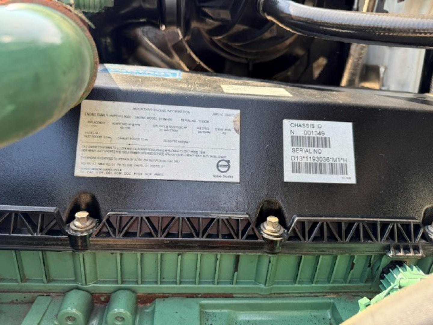 View of engine bay area on a 2018 Volvo VNR64T300 showing chassis/serial sticker labels with VIN and barcode, and nearby components.