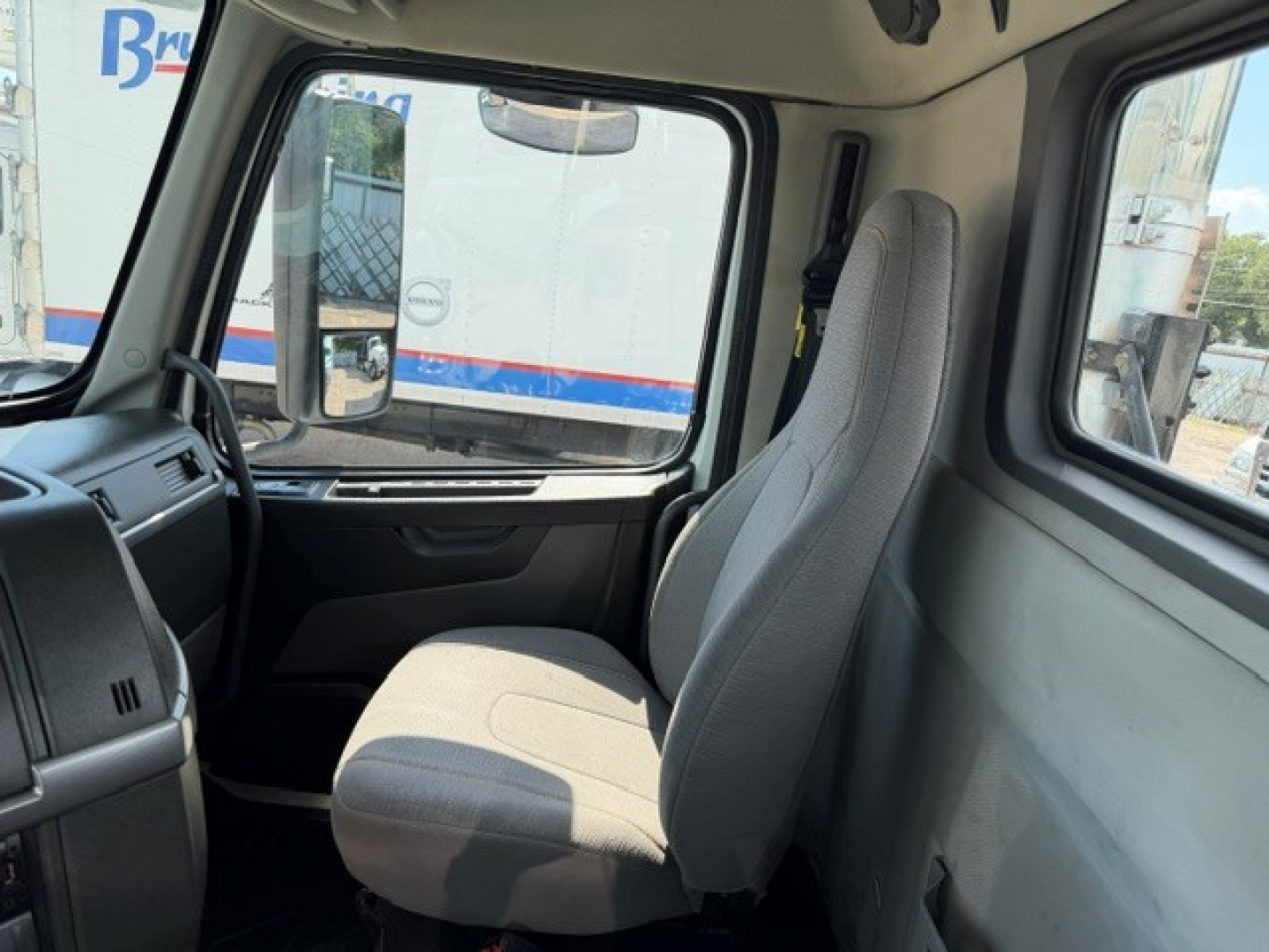 Volvo VNR64T300 truck cab interior showing driver seat and side window with clean fabric seats and dash area.