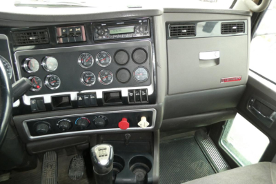 Dashboard of Kenworth T660 cab showing multiple gauges, control panels, gear shifter, and cup holders.