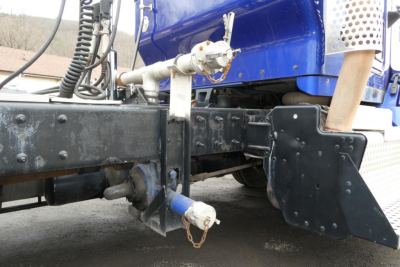 Kenworth T660 front undercarriage showing chassis, hitch, and step/board with blue cab in background.