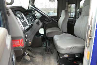 Cab interior of a 2013 Kenworth T660 conventional daycab showing steering wheel, dashboard, driver seat, and passenger seat.