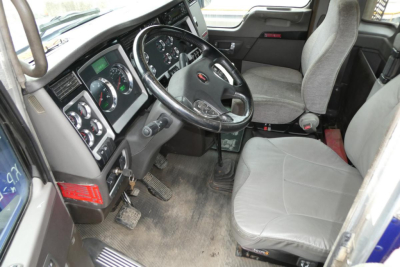 Kenworth T660 cab interior showing steering wheel, dashboard gauges, and front seats.