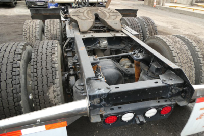 Kenworth truck rear-view showing fifth wheel and dual rear axles with dual-tuel tires and chassis. Visible are taillights and frame supports.