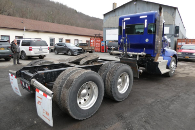 Kenworth T660 truck chassis with blue cab, rear view showing dual rear axles and mud flaps.