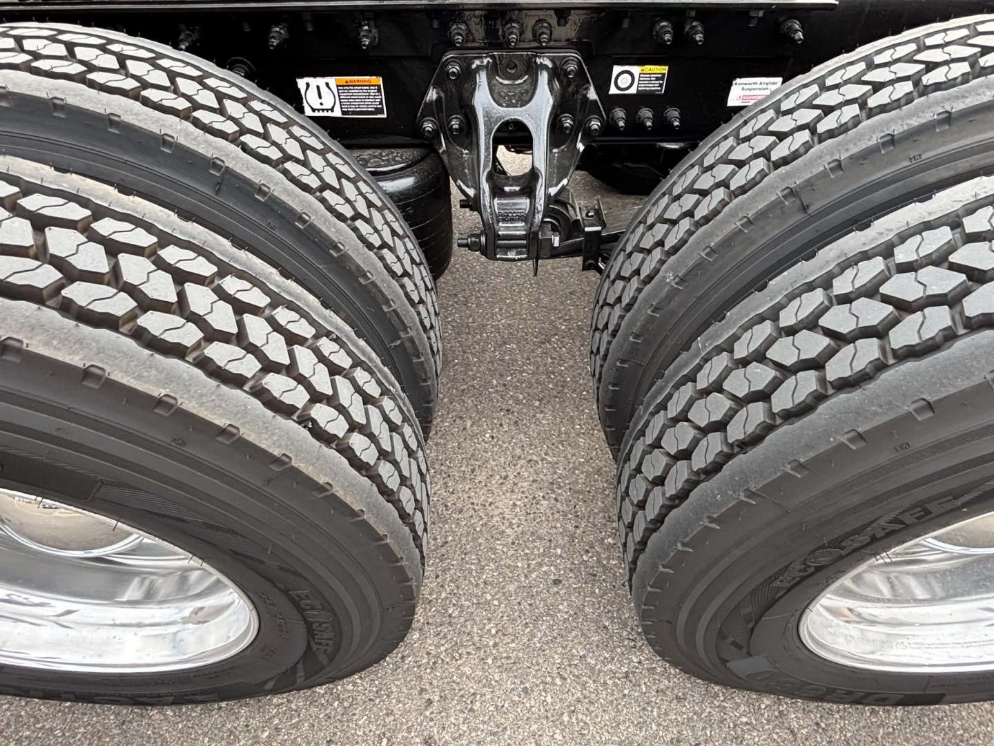 Kenworth T680 truck rear chassis with dual rear axles and dual tires, suspension components, and frame visible between wheels.